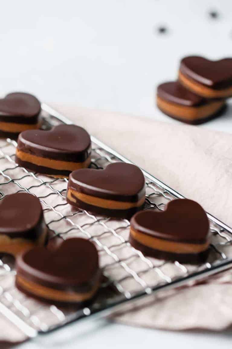 Heart shaped keto peanut butter cups on a cooling rack.