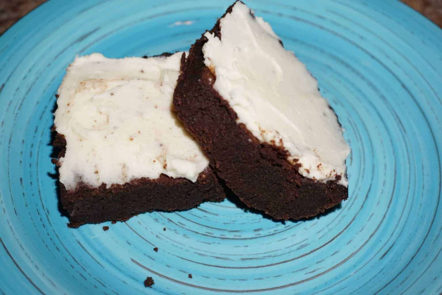 Ultimate fudge keto brownies with keto cream cheese frosting on a plate.