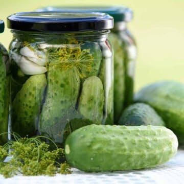 Fermented Foods: Two jars of pickles with loose pickles laying on table.