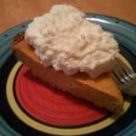 slice of low-carb pumpkin pie with almond crust topped with whipped cream on a plate