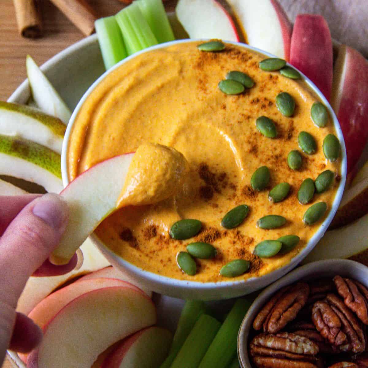 Healthy pumpkin pie dip served with apple slices and pecans.