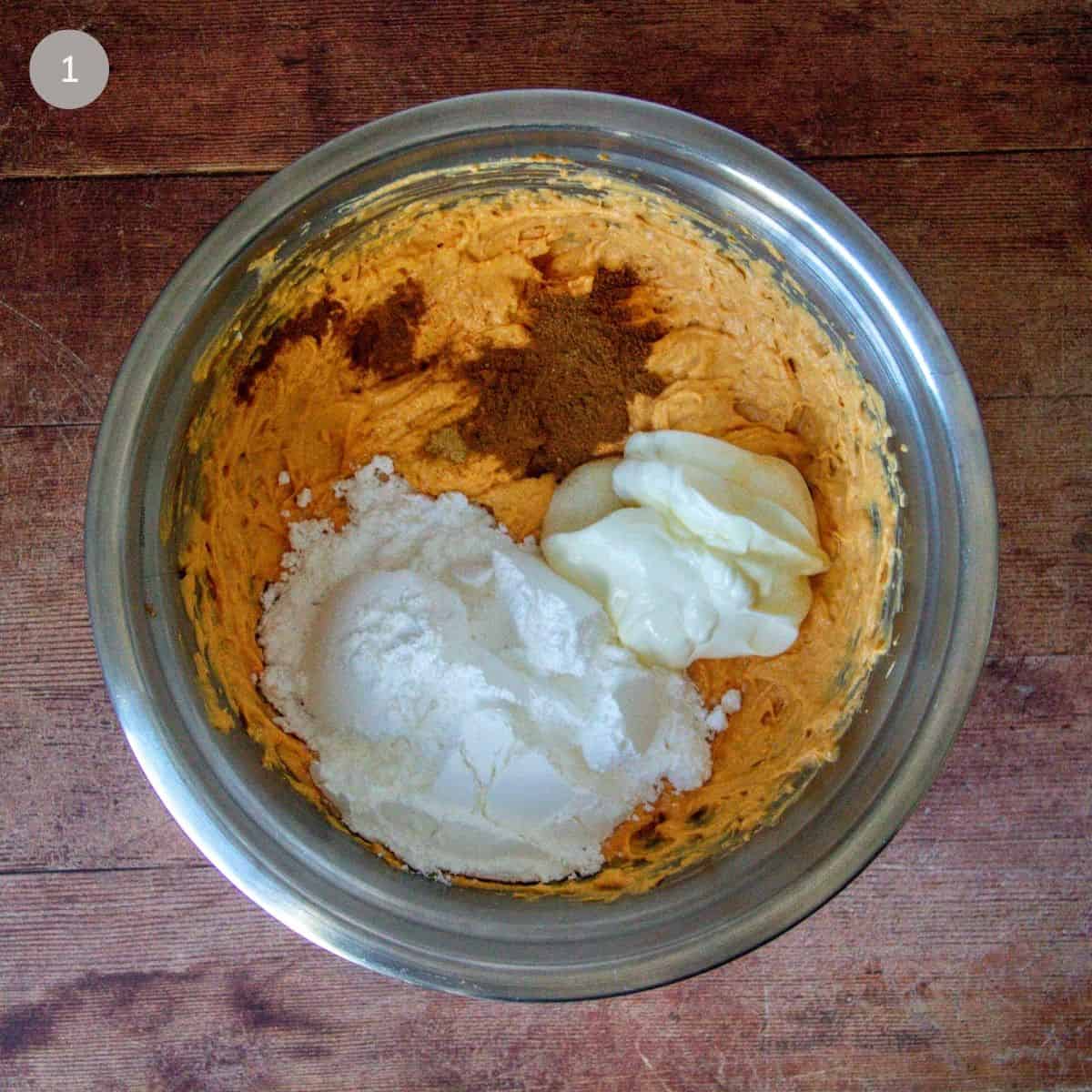 Mixing bowl with pumpkin pie dip ingredients including cream cheese and spices.