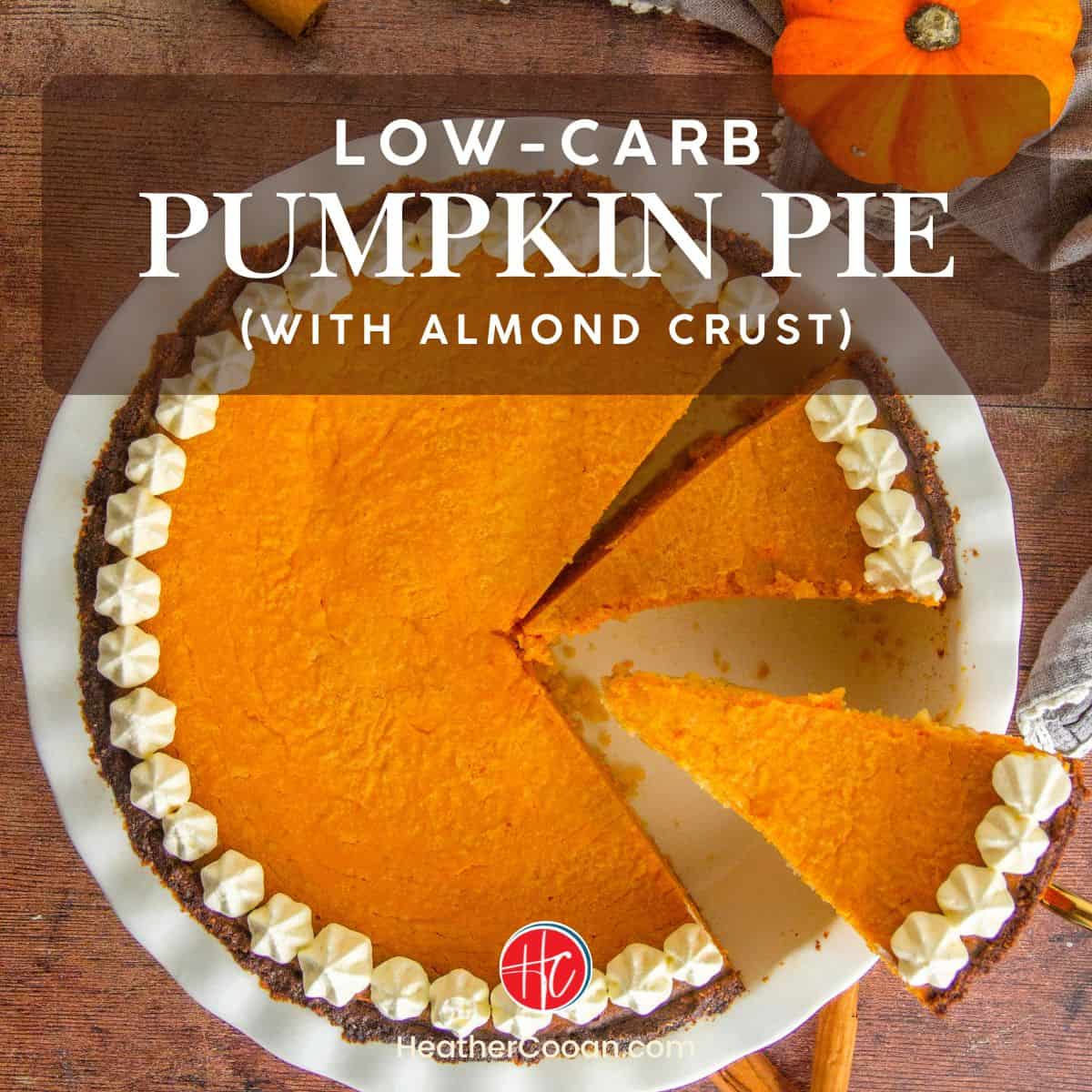 Low-carb pumpkin pie with a golden almond crust, garnished with a dollop of whipped cream on a white plate.