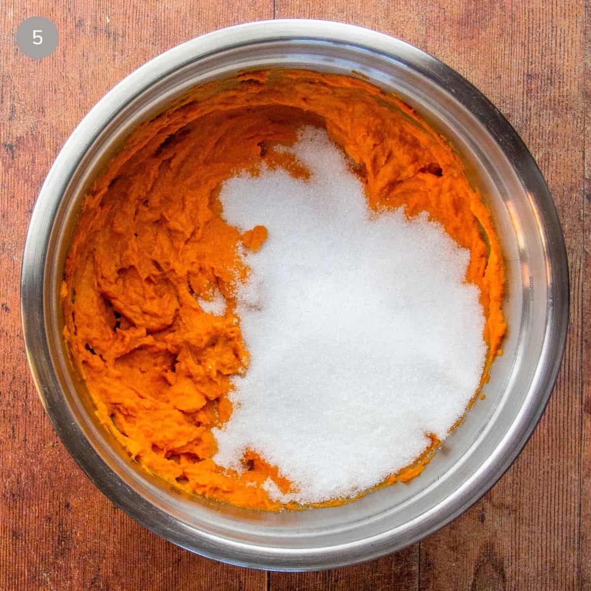 A bowl of erythritol and salt added to the cream cheese and pumpkin mixture in a metal bowl.