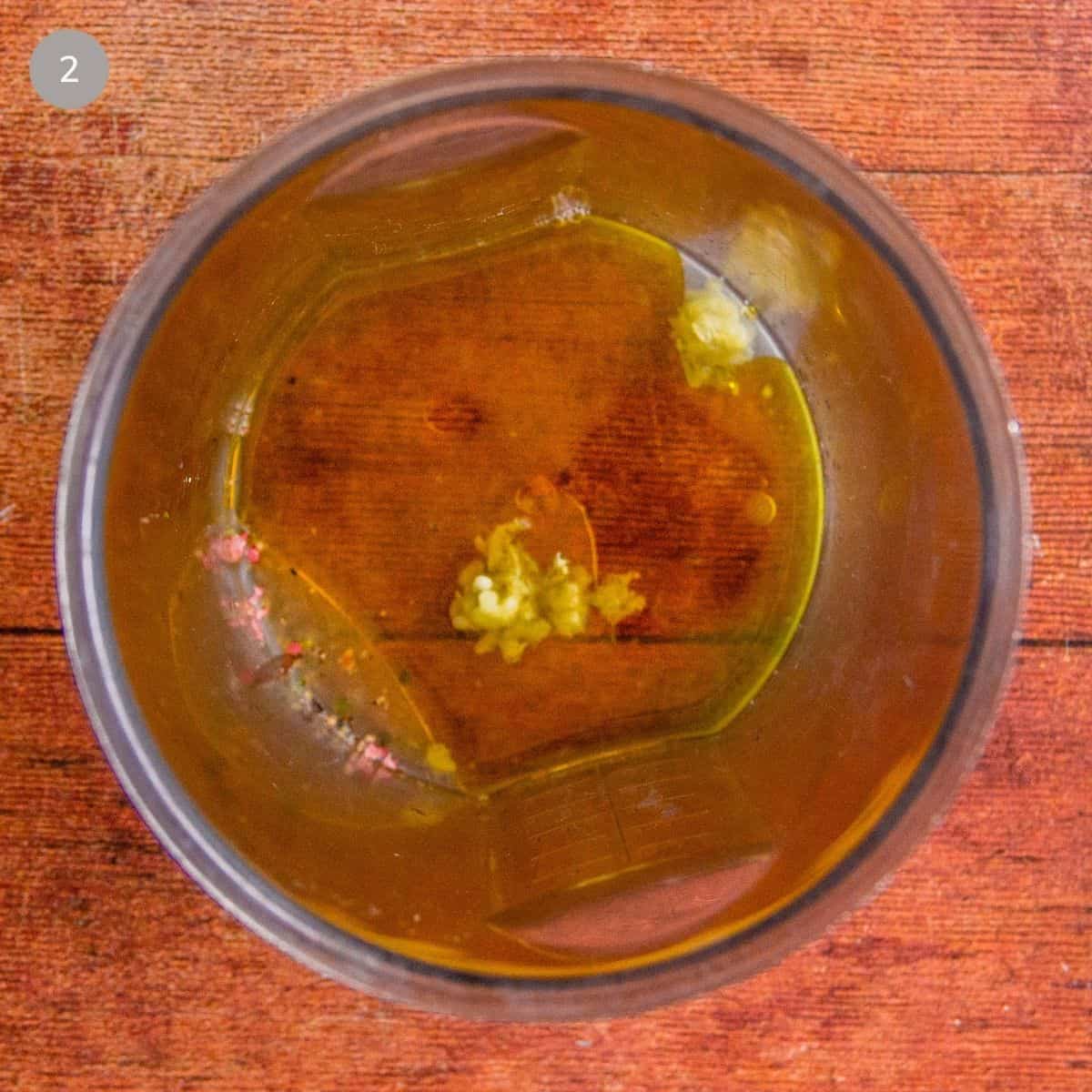 Lemon juice, oil, garlic, and pepper combined in a small blender cup.