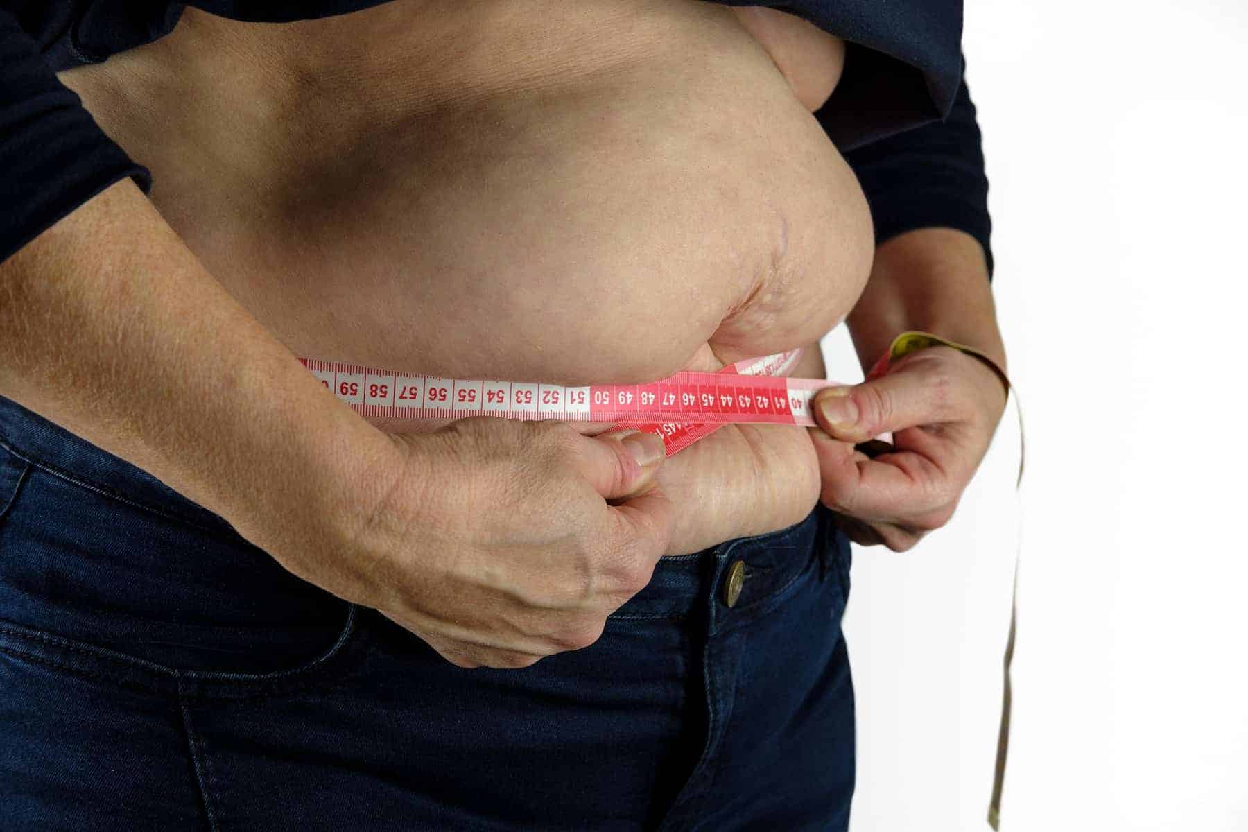 6 Major Milestones of the Modern Diet - Overweight woman measuring belly with measuring tape