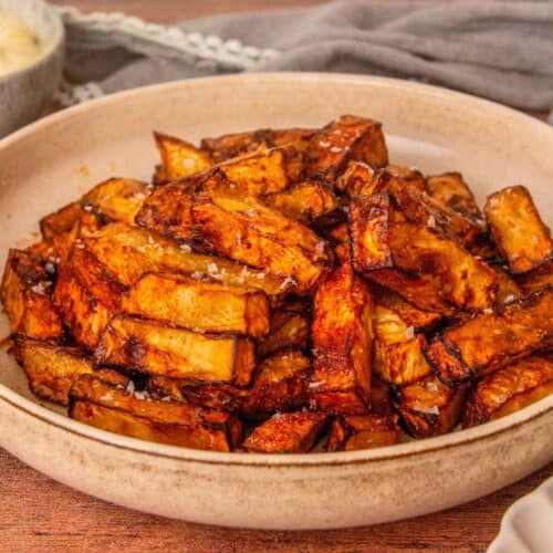 Golden, dark-edged celery root fries dusted with paprika sit in a beige bowl.