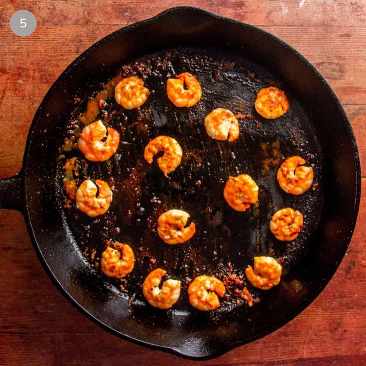Cooked, browned shrimp arranged in a cast iron skillet.