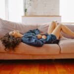 What is SIBO? Woman lying on couch clutching stomach