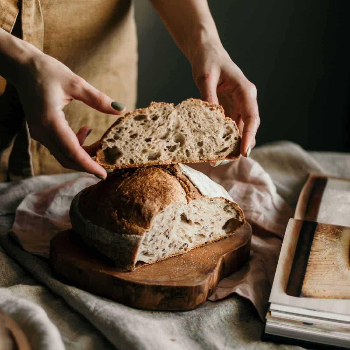 woman in apron holding sliced sourdough bread loaf