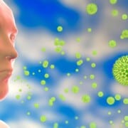 Side profile of a digital man breathing in green pollen particles on a blue and white background.