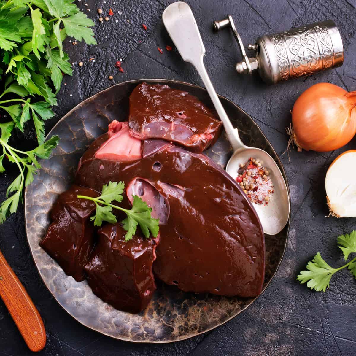 Fresh beef liver on a plate with a spoon full of spices.