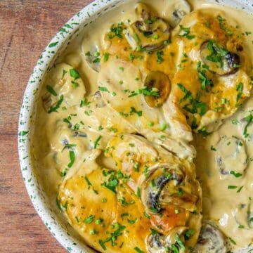 Chicken in creamy Dijon mushroom sauce, topped with parsley, served in a speckled ceramic bowl.